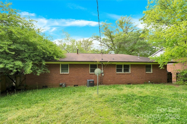 back of property with crawl space, central air condition unit, brick siding, fence, and a yard