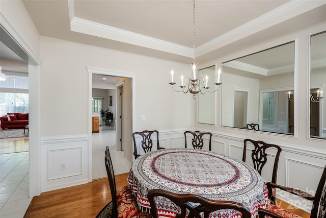 dining space with a decorative wall, a chandelier, wood finished floors, and a wainscoted wall
