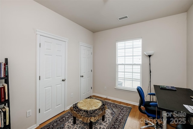 office space with baseboards, wood finished floors, and visible vents