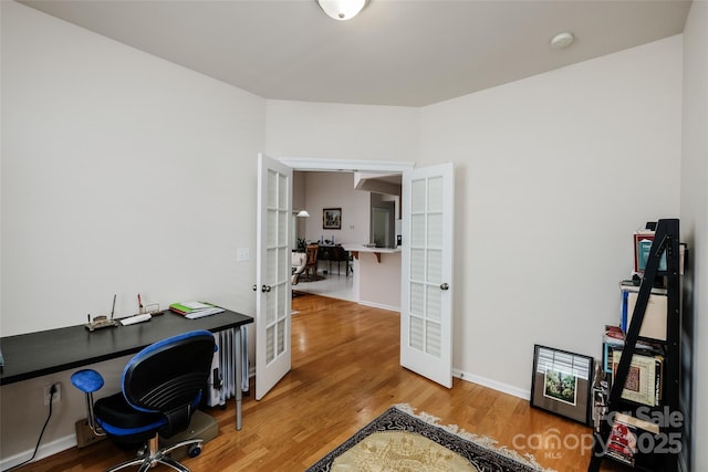home office featuring baseboards, french doors, radiator, and wood finished floors