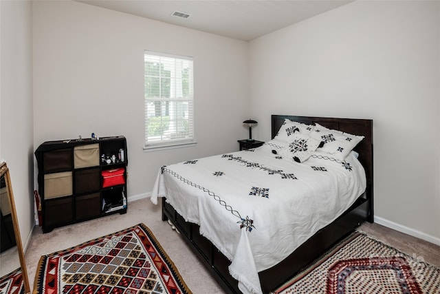 bedroom with baseboards, visible vents, and light carpet