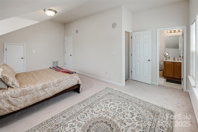 bedroom featuring visible vents, lofted ceiling, light carpet, baseboards, and ensuite bathroom