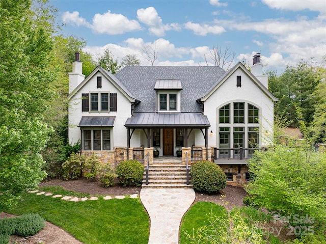 view of front of property with a porch, stucco siding, a chimney, and a standing seam roof