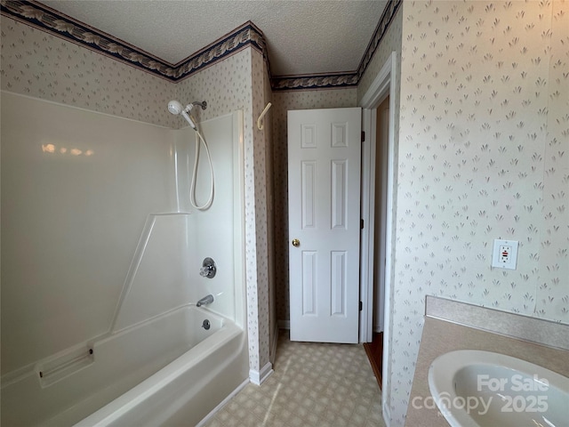 bathroom with tile patterned floors, wallpapered walls, shower / bath combination, a sink, and a textured ceiling