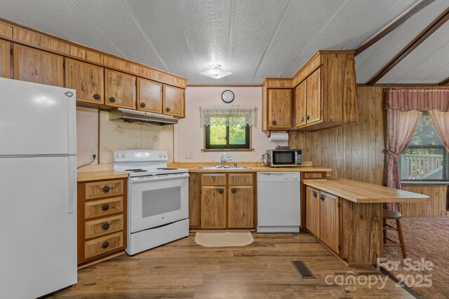 kitchen featuring visible vents, white appliances, light countertops, under cabinet range hood, and a sink