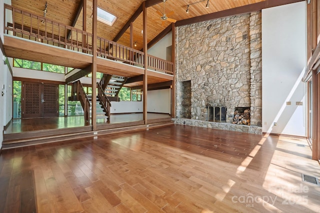 unfurnished living room with visible vents, high vaulted ceiling, wood ceiling, hardwood / wood-style flooring, and a skylight