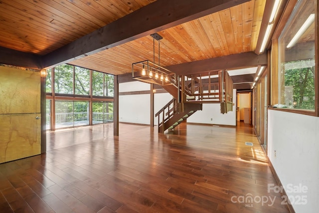 unfurnished living room featuring stairs, beam ceiling, and wood finished floors