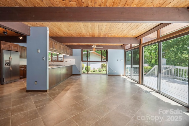 kitchen featuring beam ceiling, stainless steel fridge, light countertops, wood ceiling, and a ceiling fan