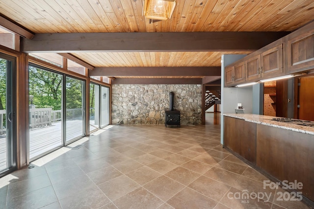 interior space featuring tile patterned flooring, light stone countertops, a wood stove, beam ceiling, and wooden ceiling
