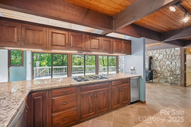 kitchen with a wood stove, wooden ceiling, light stone counters, stainless steel gas stovetop, and light tile patterned flooring