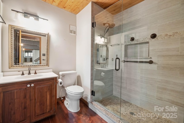full bath with visible vents, a shower stall, wood finished floors, vanity, and toilet
