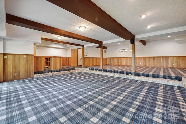 finished below grade area with wood walls, wainscoting, a textured ceiling, and carpet flooring