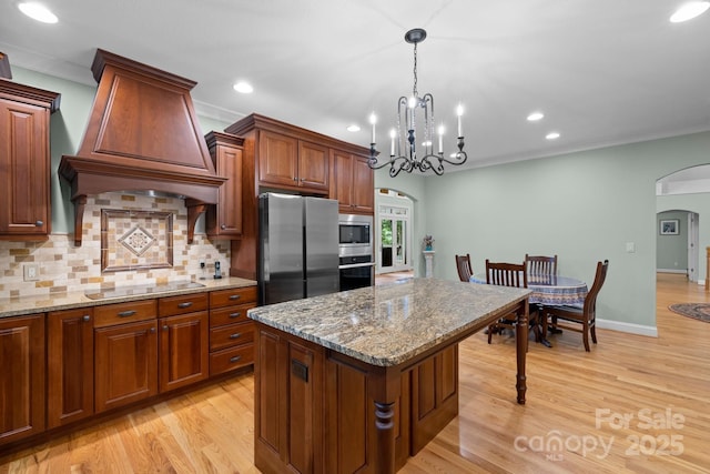206 Stone Valley Way Unit 23, Hendersonville, NC 28792 - kitchen featuring arched walkways, appliances with stainless steel finishes, custom exhaust hood, tasteful backsplash, and light wood finished floors