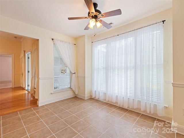 spare room featuring light tile patterned floors, baseboards, and a ceiling fan