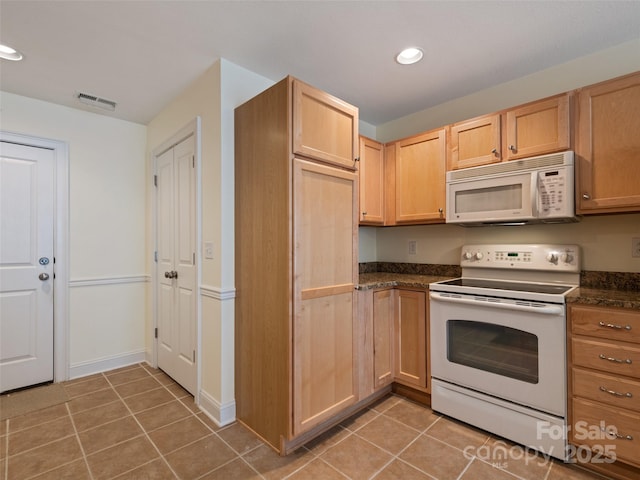kitchen featuring visible vents, dark countertops, light tile patterned flooring, and white appliances