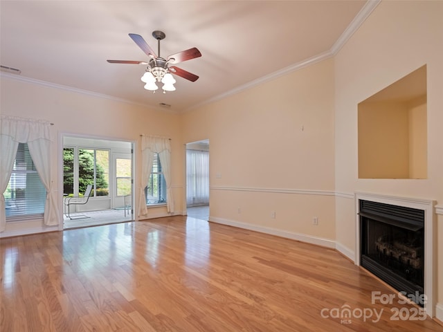 unfurnished living room with crown molding, ceiling fan, a fireplace, baseboards, and light wood-type flooring