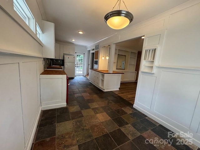 1019 Valley St, Kannapolis, NC 28081 - kitchen featuring freestanding refrigerator, a decorative wall, stone tile flooring, wood counters, and white cabinetry