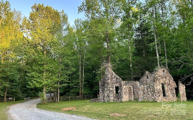 view of property's community with a yard, a forest view, and fence