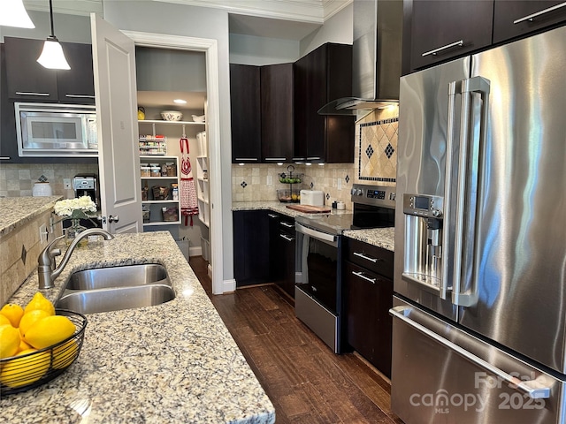 kitchen featuring dark wood-type flooring, wall chimney exhaust hood, a sink, appliances with stainless steel finishes, and backsplash