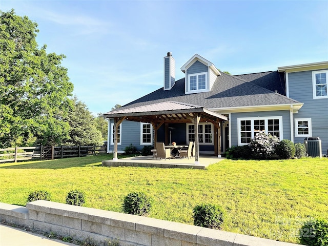 back of property with a gazebo, a chimney, cooling unit, a patio, and a yard
