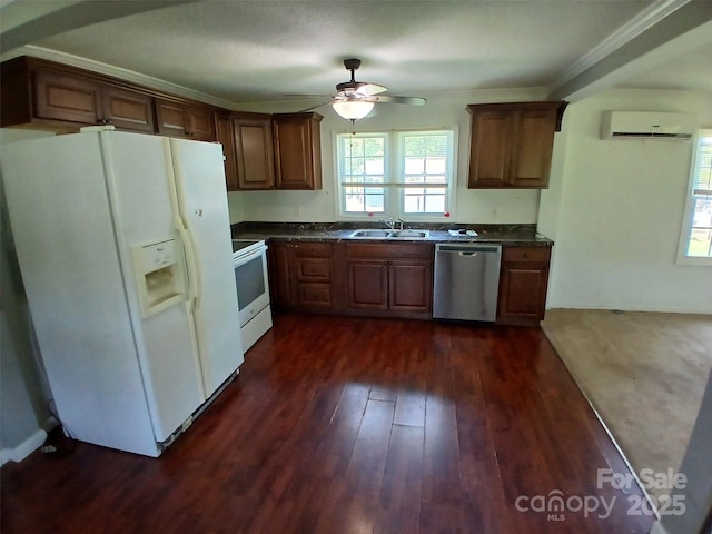 kitchen with a sink, dark countertops, white appliances, a wall mounted AC, and a ceiling fan