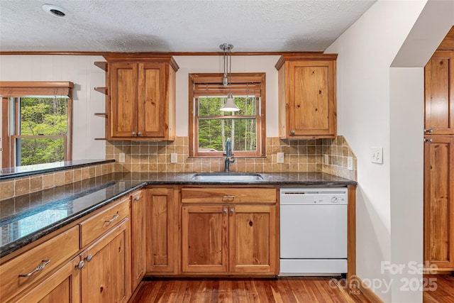 kitchen featuring white dishwasher, a textured ceiling, brown cabinets, and a sink