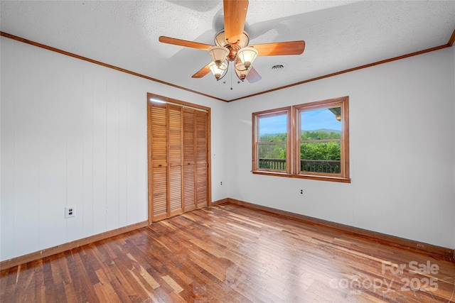 unfurnished bedroom with crown molding, baseboards, visible vents, and hardwood / wood-style floors