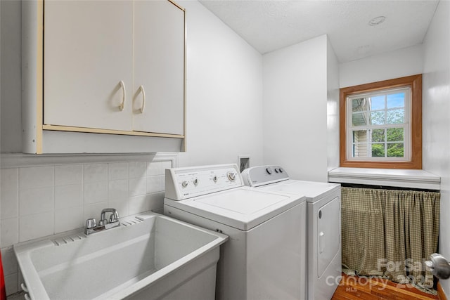 washroom with washer and dryer, a textured ceiling, a sink, and cabinet space