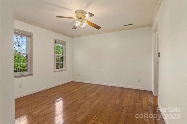 spare room featuring visible vents, ornamental molding, ceiling fan, and wood finished floors