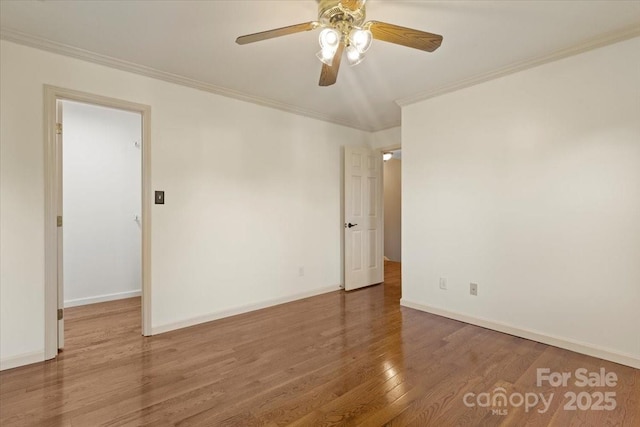 empty room with wood finished floors, crown molding, a ceiling fan, and baseboards