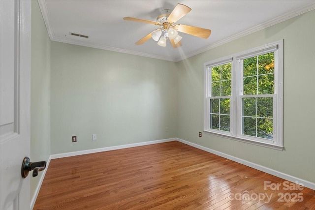 spare room with ornamental molding, visible vents, wood finished floors, and baseboards