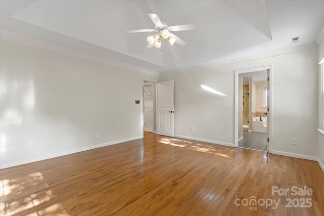 spare room with ornamental molding, ceiling fan, light wood-style flooring, and baseboards