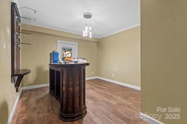 interior space with baseboards, ornamental molding, wood finished floors, and decorative light fixtures