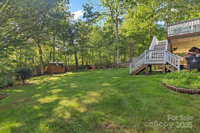 view of yard featuring a fenced backyard, stairway, an outbuilding, a storage shed, and a wooden deck