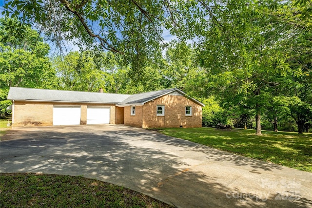 view of front facade with driveway, a chimney, a front yard, brick siding, and a garage