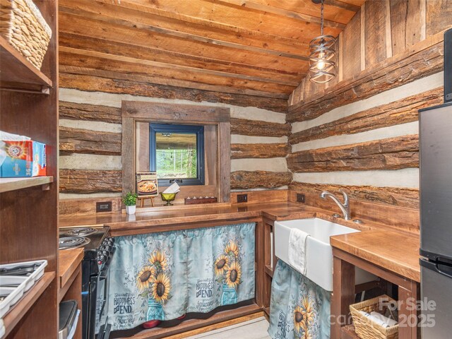 interior space featuring freestanding refrigerator, black electric range oven, wooden walls, wood ceiling, and hanging light fixtures