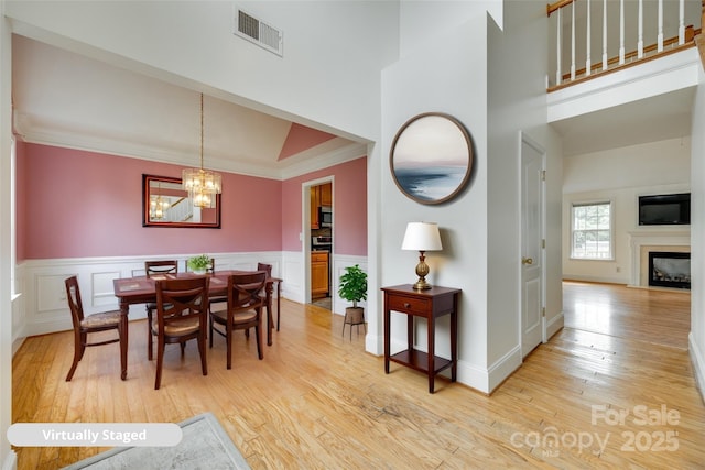 1835 Montague Rd, Clover, SC 29710 - dining space featuring light wood-type flooring, ornamental molding, wainscoting, a fireplace, and a high ceiling