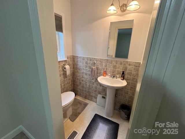 323 Hibriten Dr SE, Lenoir, NC 28645 - bathroom with toilet, tile walls, wainscoting, and tile patterned flooring