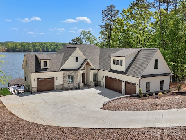 8044 Edgewater Dr Unit 100, Norwood, NC 28128 - modern inspired farmhouse featuring concrete driveway, stone siding, a garage, roof with shingles, and a water view