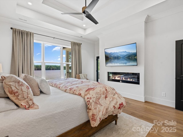 8044 Edgewater Dr Unit 100, Norwood, NC 28128 - bedroom with a raised ceiling, wood finished floors, a glass covered fireplace, recessed lighting, and baseboards