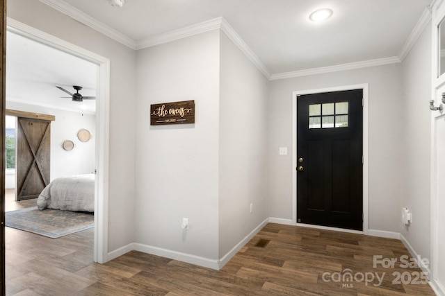 foyer entrance featuring crown molding, baseboards, and wood finished floors
