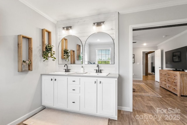 bathroom with a sink, crown molding, and double vanity