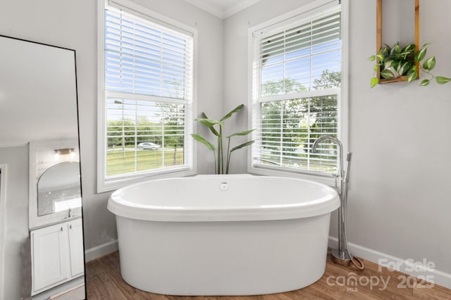 full bath featuring a freestanding tub, baseboards, and wood finished floors