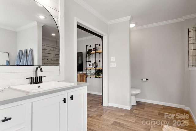 bathroom featuring vanity, ornamental molding, baseboards, and wood finished floors
