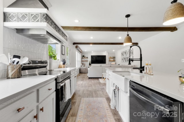 kitchen with a sink, appliances with stainless steel finishes, white cabinets, and beamed ceiling