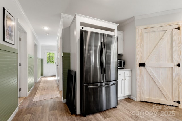 kitchen featuring baseboards, freestanding refrigerator, light wood-style flooring, and white cabinets