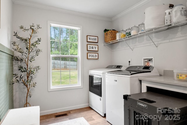 clothes washing area featuring laundry area, visible vents, crown molding, washing machine and clothes dryer, and light wood-type flooring