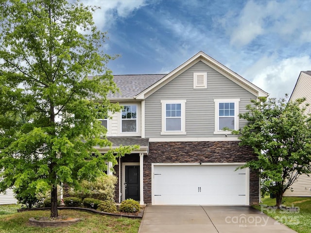 traditional home with driveway, a garage, roof with shingles, and stone siding