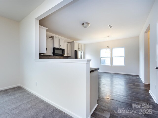 kitchen featuring black microwave, visible vents, baseboards, decorative light fixtures, and stainless steel fridge