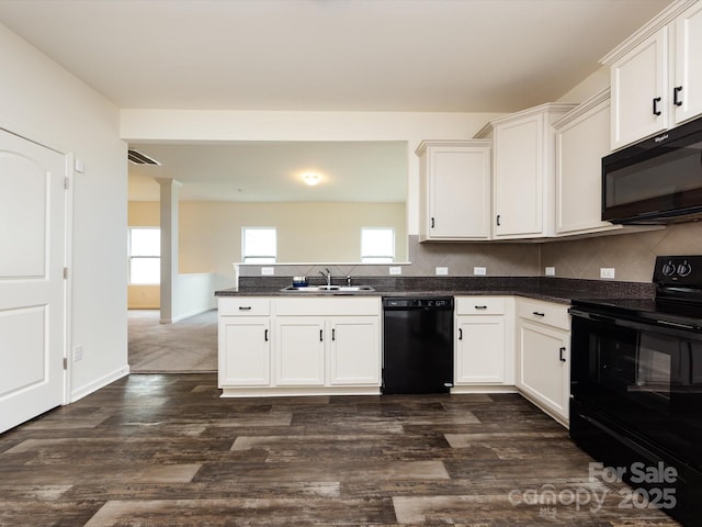 kitchen featuring a sink, black appliances, a peninsula, dark countertops, and white cabinets